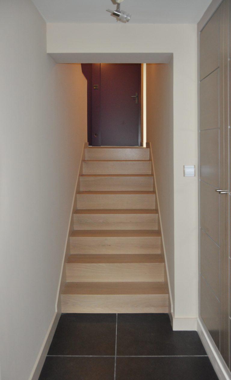 escalier en bois clair avec demi-mur à côté d'un riche mur violet